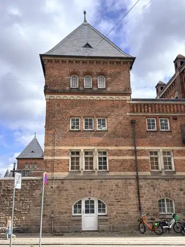 Oversigtsbillede af gade mod tårn facade på gadefacaden, i tegl, mørtel, natursten og sandsten.