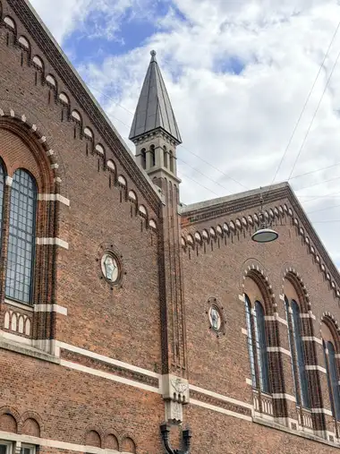 Billede af tegl hjørne tårn på gadefacaden, i tegl, mørtel, natursten og metal.
