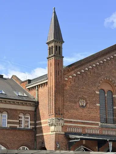 Billede af facade hjørne tårn set fra forpladsen, i tegl, mørtel, natursten og skifer.