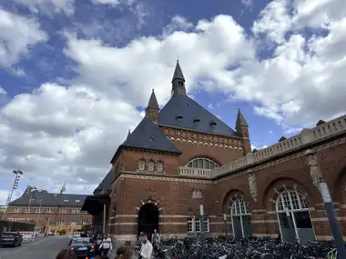 Oversigtsbillede af hoved station indgang facade set fra forpladsen, i tegl, natursten, mørtel og skifer.