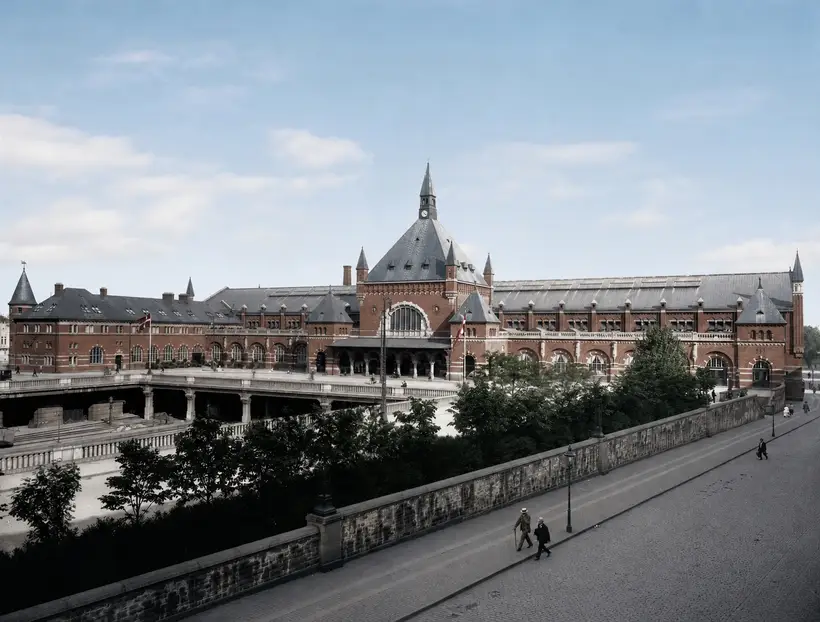 Banegårdens lange facade set fra oven, med forpladsen båret hen over en sporgrav og en stenbalustrade i forgrunden.