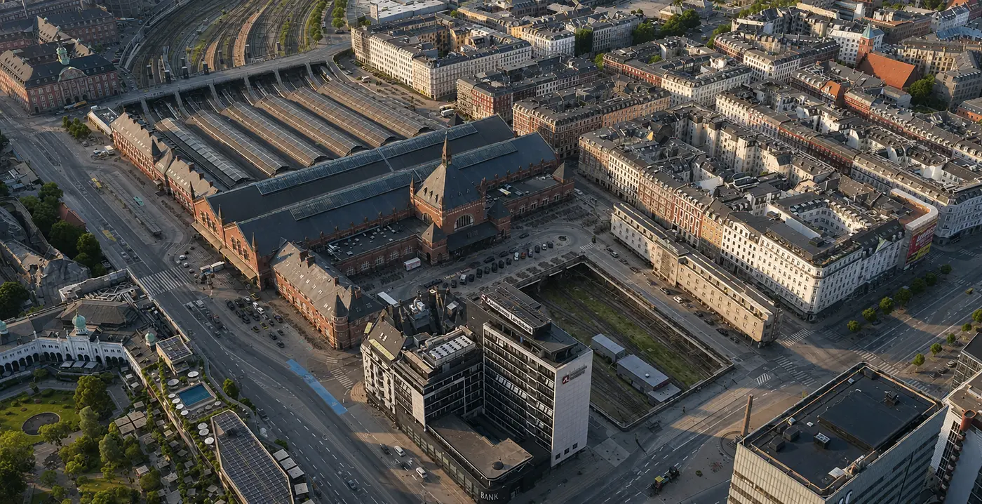 Banegården højt fra nordøst: forpladsen og indgangsbygningen forrest, og bag den de seks perronhaller, der løber væk mod sporene.
